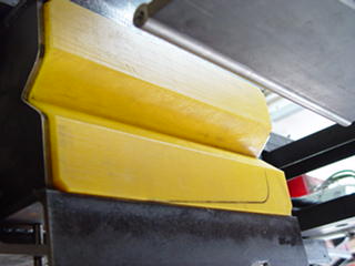Yellow and black metal part with curved edge.