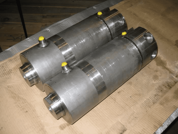 Two cylindrical metal components with yellow knobs.