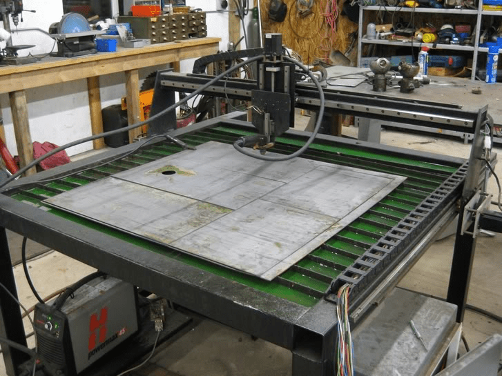 Large metal worktable with green strips and red logo in a factory workshop setting.