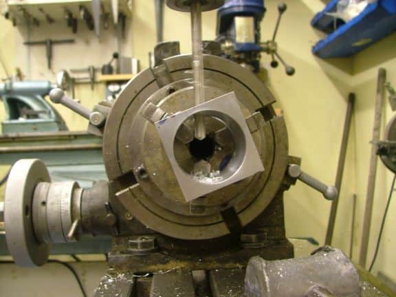 Metalworking lathe in a workshop or machine shop environment with surrounding tools and equipment.