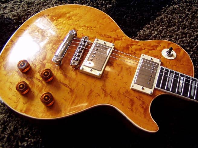 Intricate electric guitar with natural finish and single cutaway design.