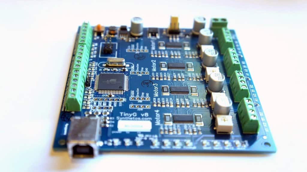 Blue circuit board with capacitors, resistors, microchips, and USB connector.