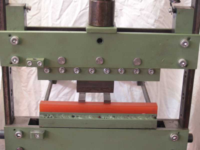 Green metal press with cylindrical component and supporting bars.