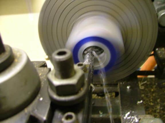 Metalworking lathe spindle with blue chuck ring visible.