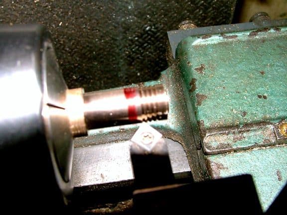 Metal object with red stripe on a dark background.