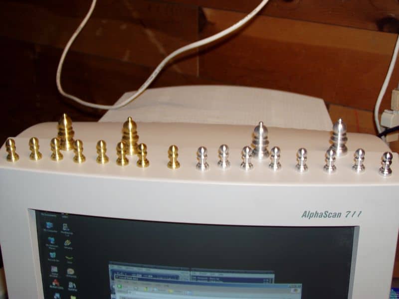 White computer monitor with icons on a black background against a wooden wall.