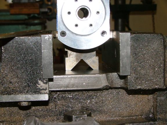 Metalworking vise on metal base with flat surface and central opening.
