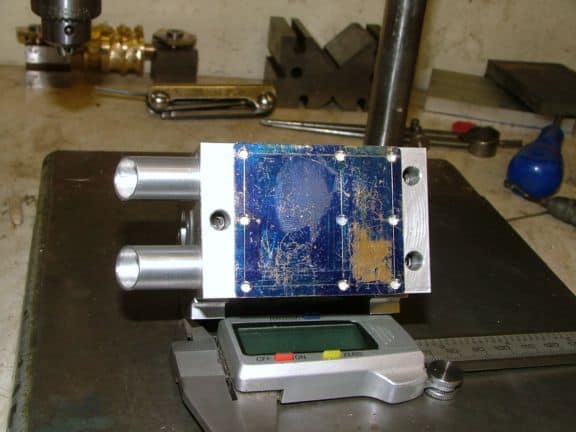 Precision measuring device with blue and silver body, digital display, and surrounding industrial tools.