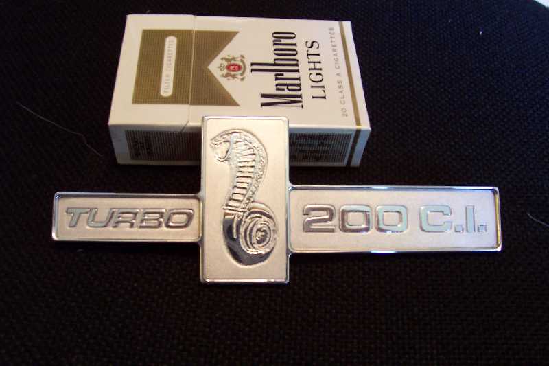 A stylized Turbo 2000 logo with integrated numbers on a black background featuring a Marlboro Lights pack.