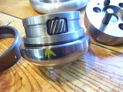 A 5C collet chuck assembly with aluminum body and black band, silver nut, on a wooden workbench.
