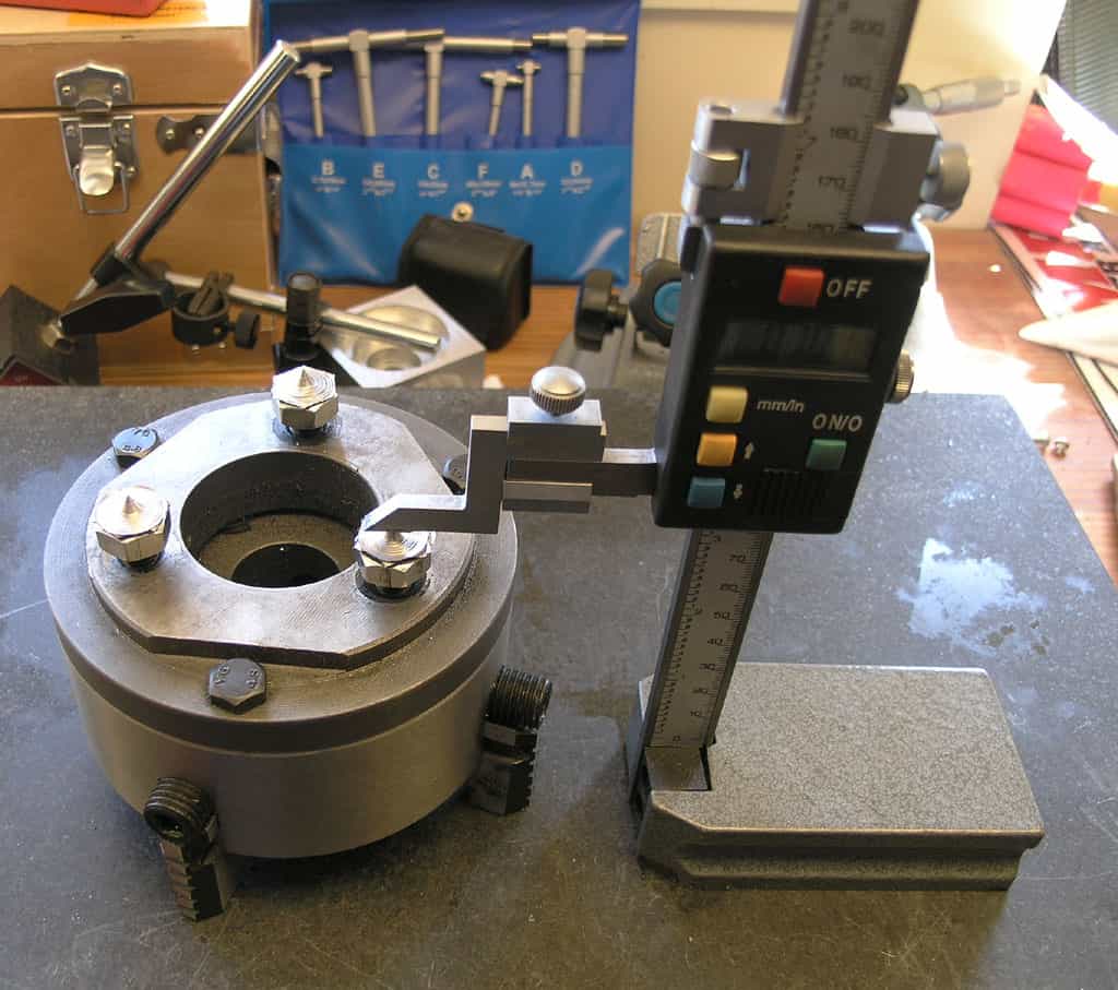 Precise measuring tool with digital display on a circular base and vertical arm.