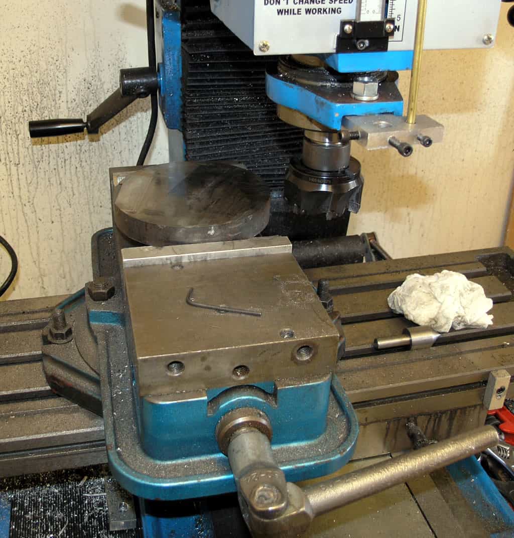 Vertical mill headstock with vise, collet, and spindle.