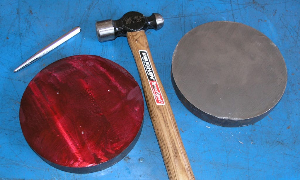 Black hammer with wood handle and various metal tools on a blue surface.