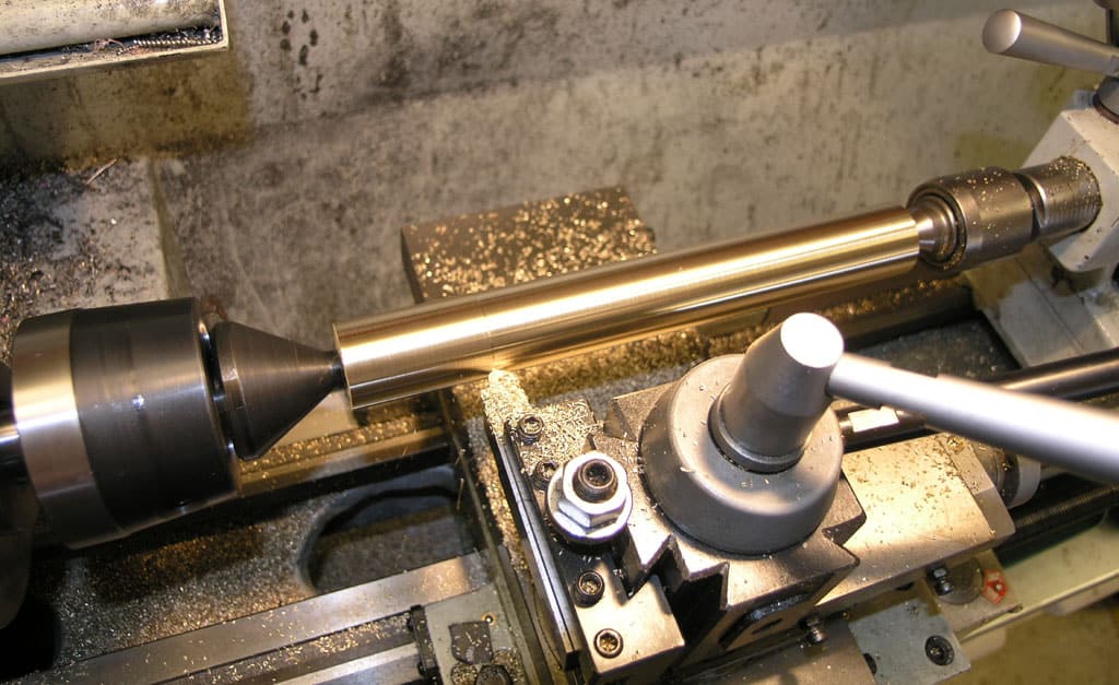 A metalworking lathe with a cylindrical workpiece being machined.