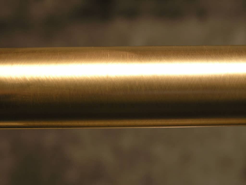 Brass pipe with smooth surface and golden hue on dark background.