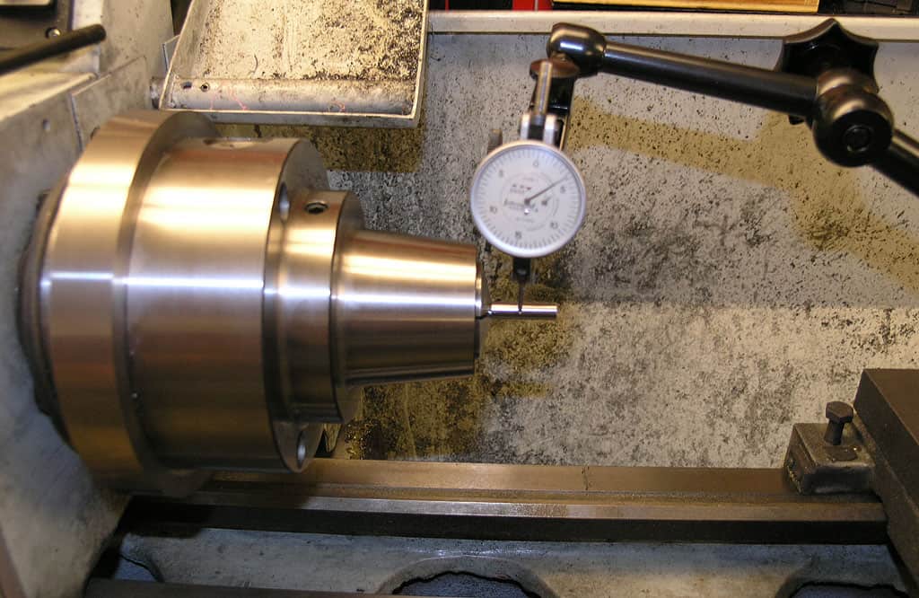 Lathe toolpost micrometer measuring cylindrical workpiece diameter.