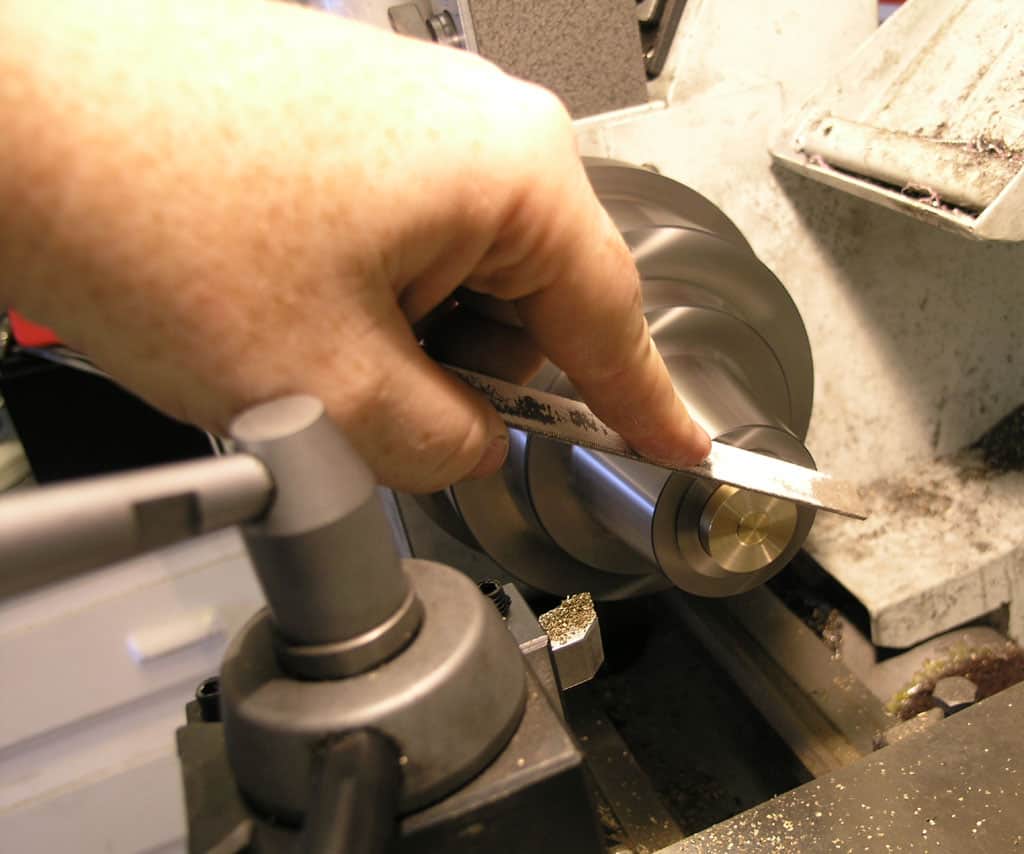 A person's hand holding a metal tool with a cylindrical shape and flat end, likely used in machining or fabrication.