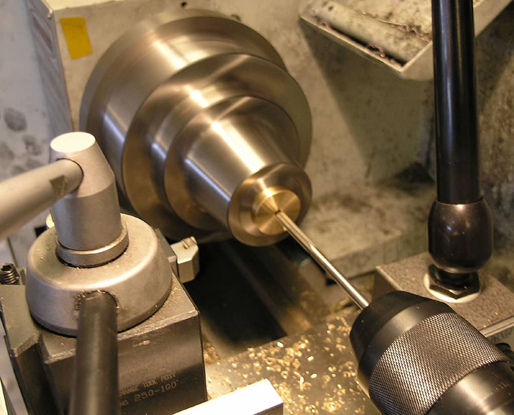 A metalworking lathe with a central spindle rotating clockwise, featuring various attachments and accessories.