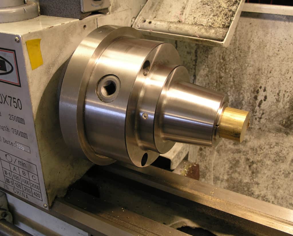 Metal lathe components on gray wall.