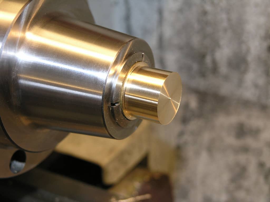 Brass or bronze cylindrical object with hexagonal hole.