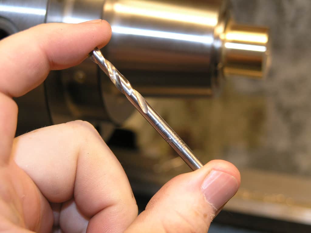A hand holds a silver metal rod with twisted design.