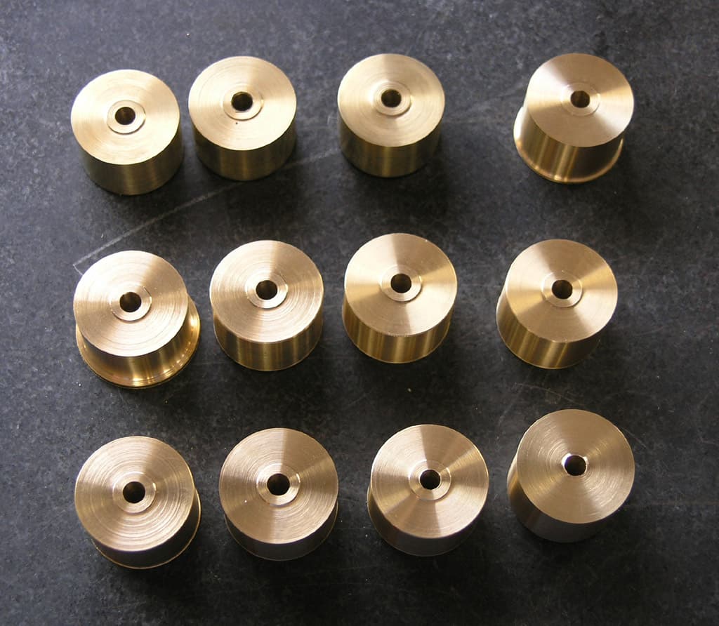 Machined cylindrical brass parts with central hole on a flat surface.