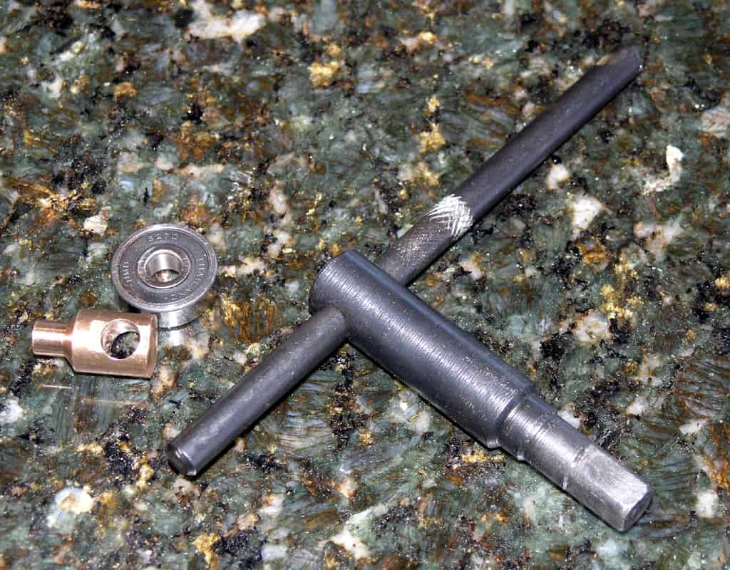 Metal parts and tools including T-handle, bearing, and other components.