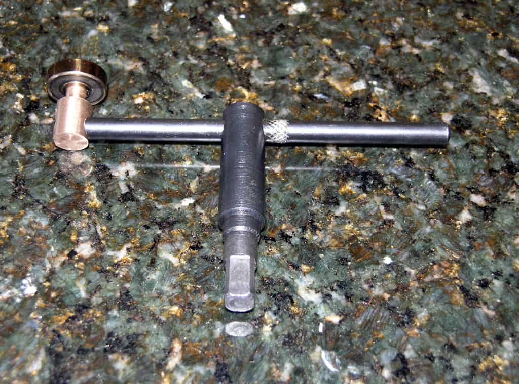 A tool with a long, thin rod and circular end on a green marble surface.
