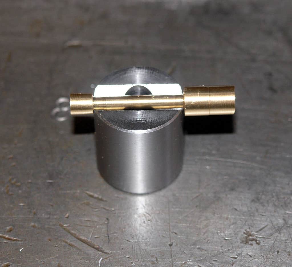 A small metal object with a cylindrical base and a brass rod.
