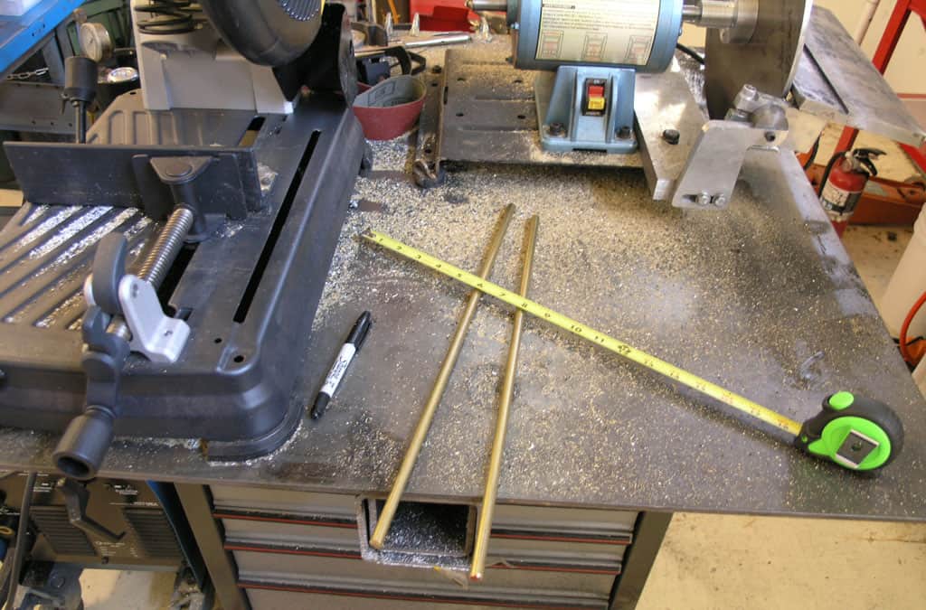 A cluttered workbench with tools, equipment, and debris in a machine shop or workshop setting.