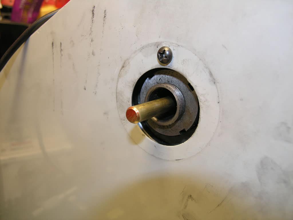 Metal component with central shaft, red tip, and white ring, attached to a metallic body.