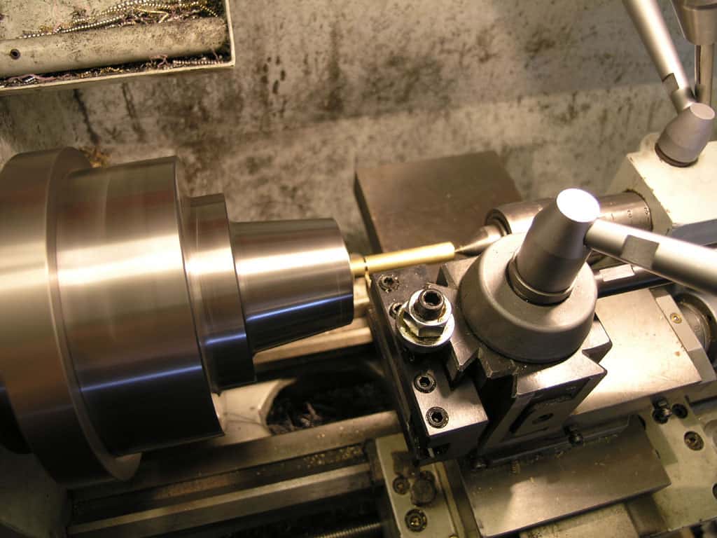Metal lathe with workpiece on bed of tooling and cutting tools.