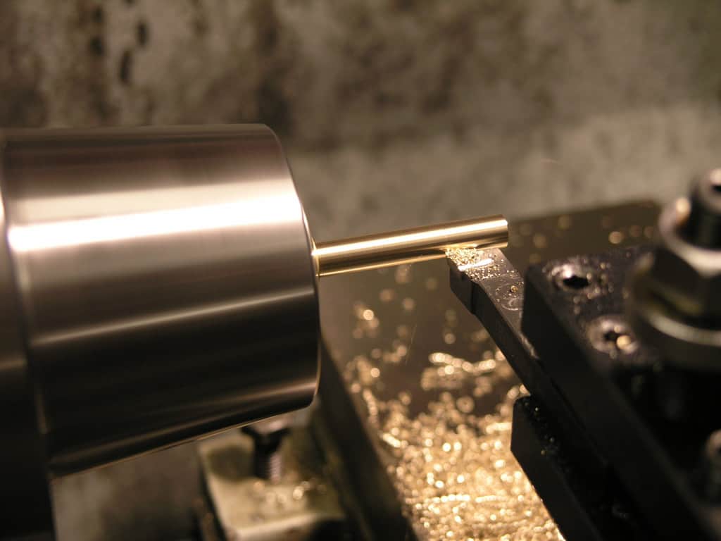 Lathe tool machining a cylindrical piece of brass.