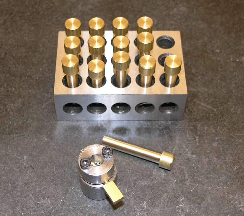Metal block with brass cylindrical protrusions on a gray background.