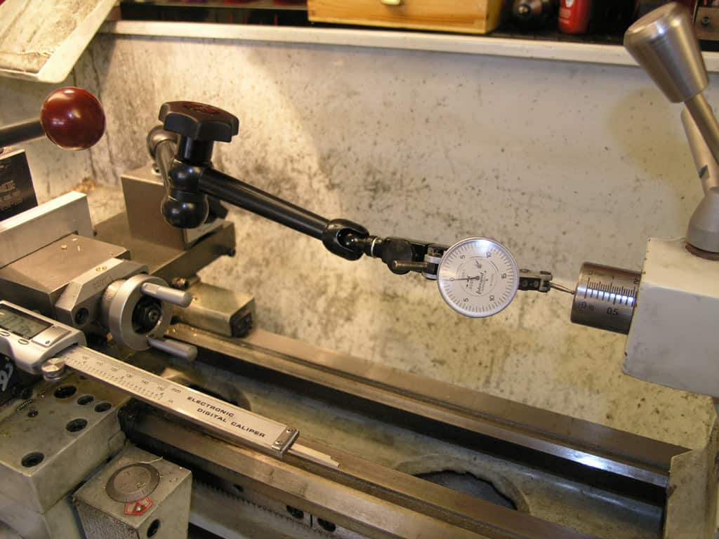 A digital electronic caliper on a lathe in a machine shop setting.