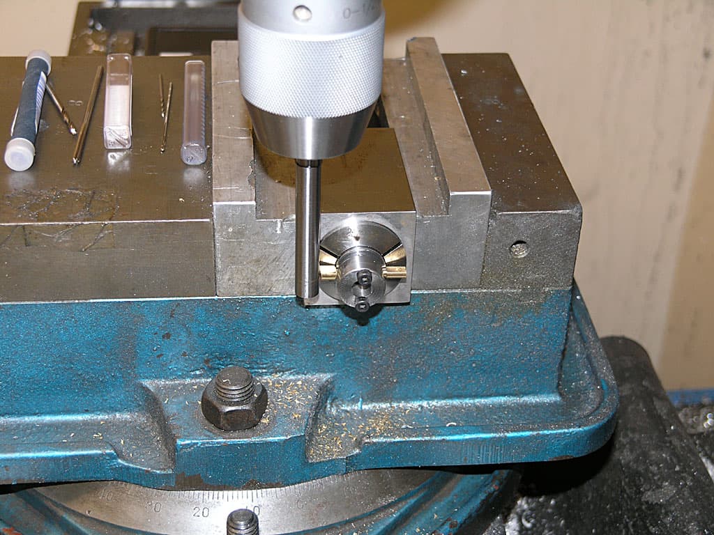 Metalworking lathe or milling machine vise with blue base plate and assorted tools.