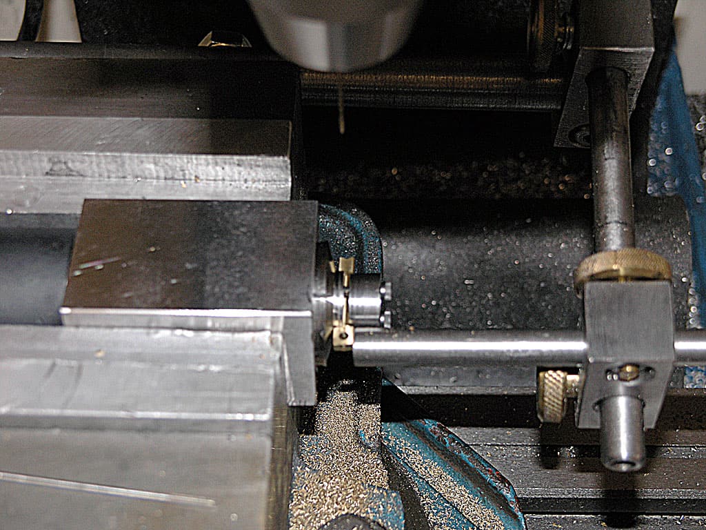 Metalworking machine with tools and parts, featuring a vice-like device and a long rod.