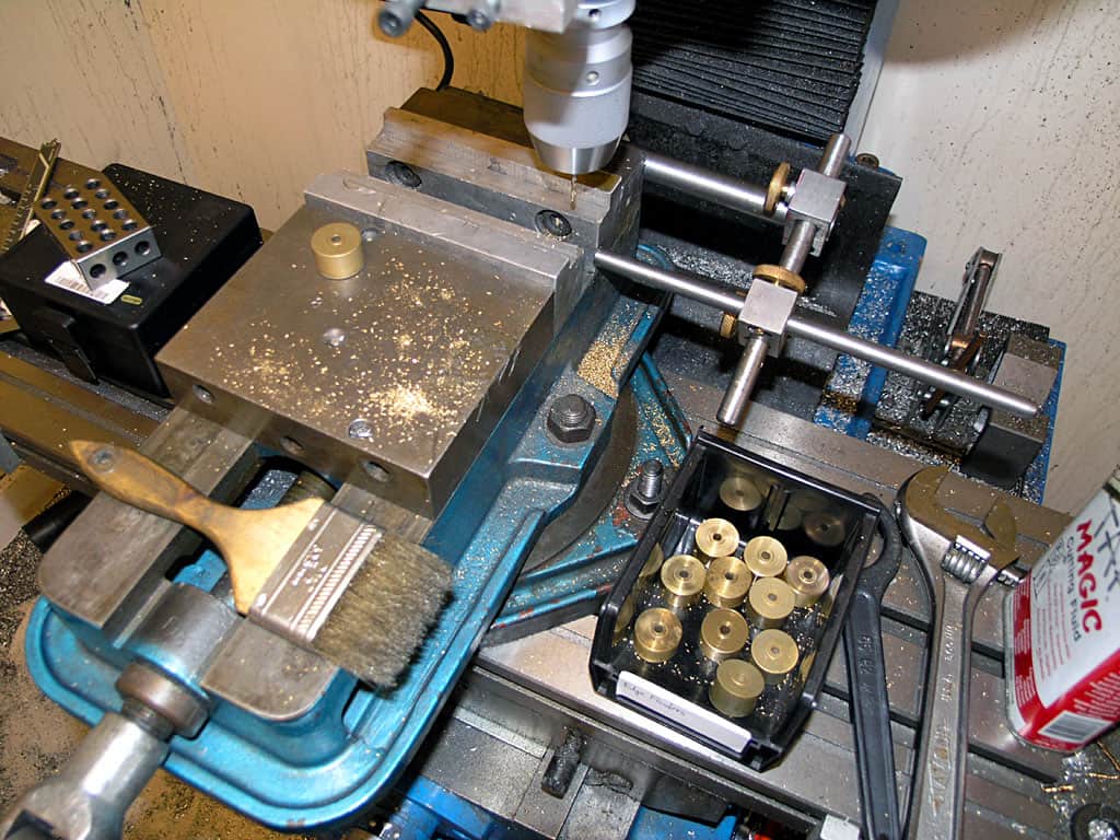 Metal fabrication and machining workshop workbench with drill press, vice, and clamps.