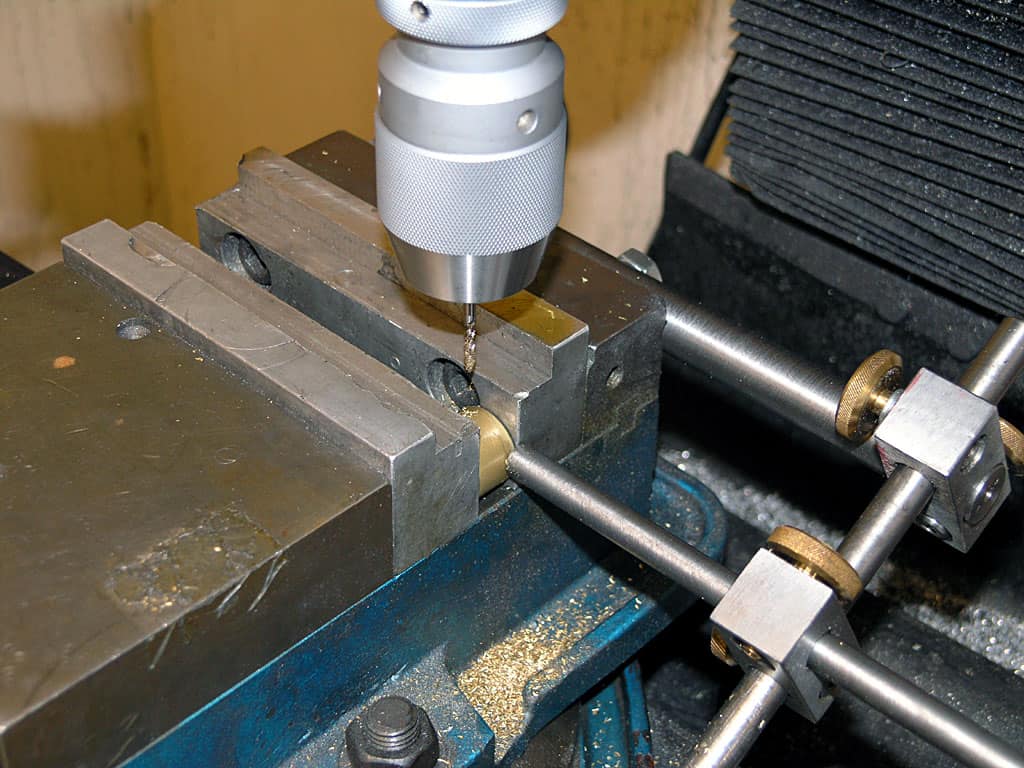 Metalworking machine in industrial setting with drill bit and support rods.