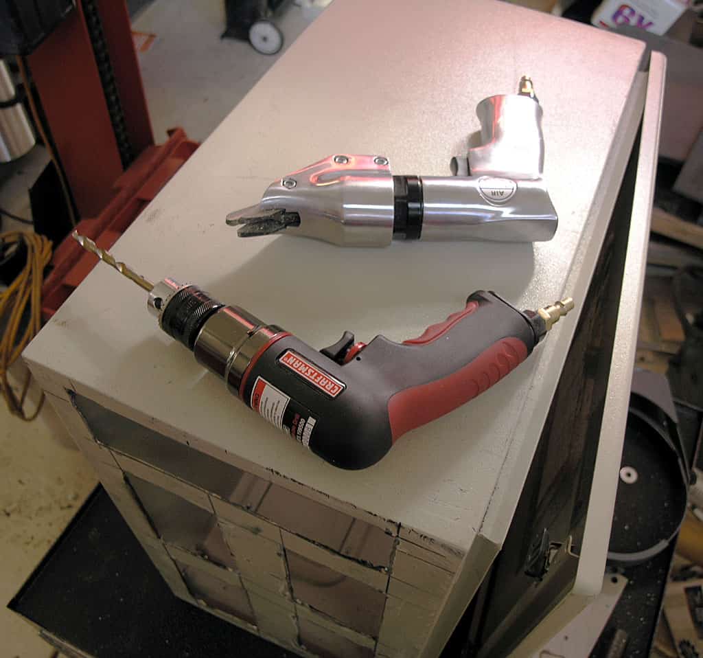 Two drills on a gray box in a workshop setting.