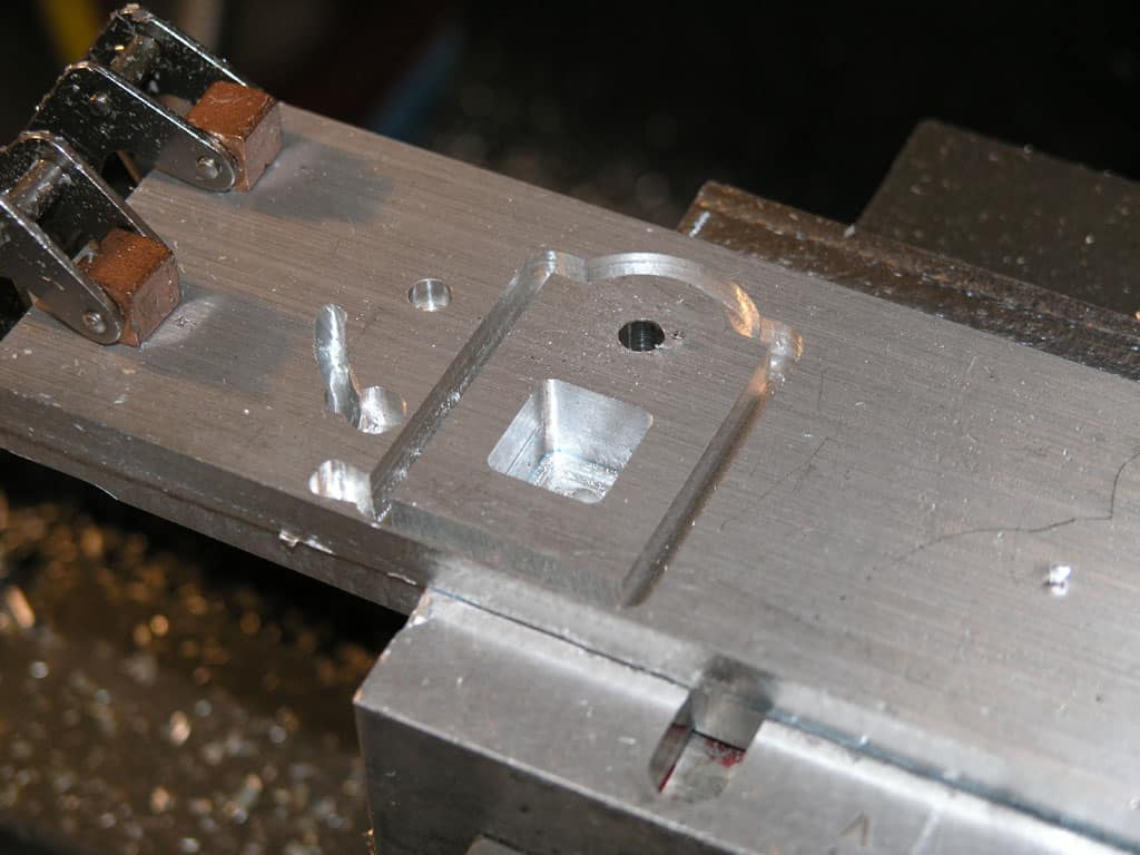 An aluminum block with various tools and metal parts attached.