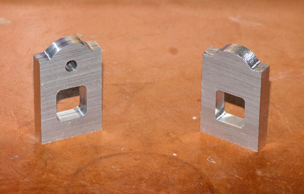 Two rectangular metal pieces with square cutouts and a curved edge.