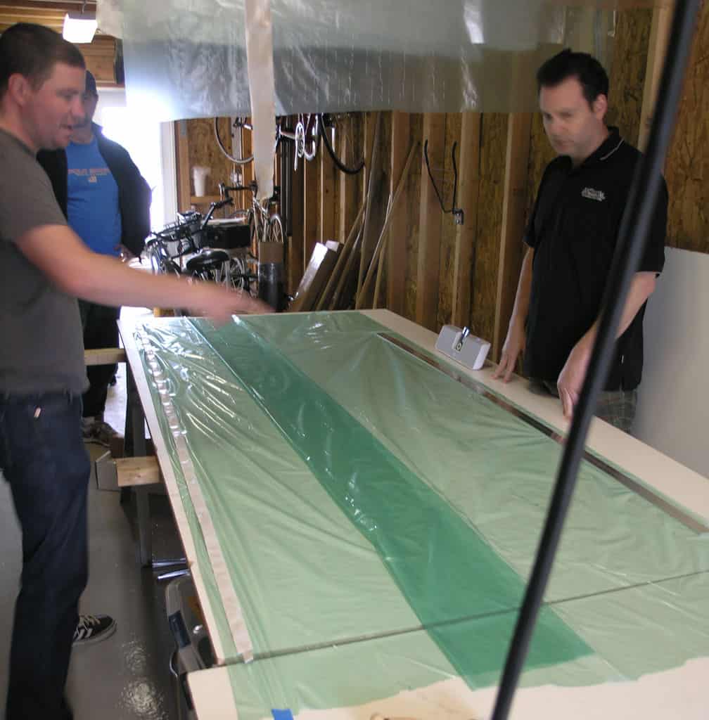 Men gathered around a worktable in a workshop or garage.