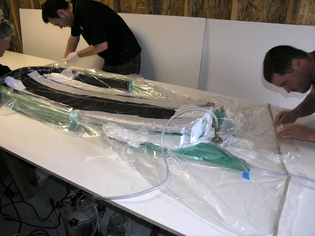 Men gathered around a large, green, plastic machine in a workshop setting.