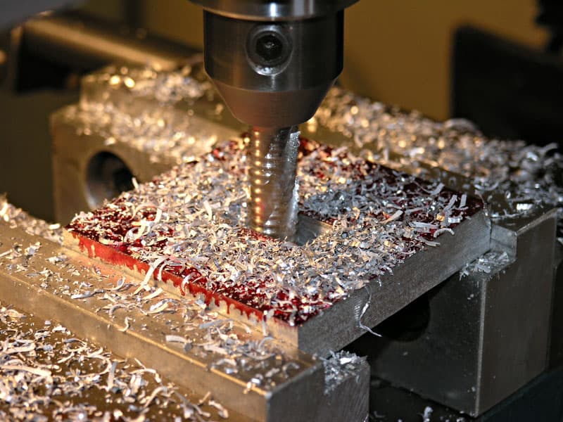 Milling machine cutting tool in operation, surrounded by shavings.