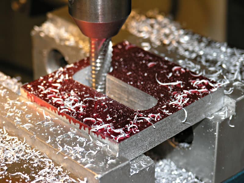 Metal workpiece being drilled with a drill bit.