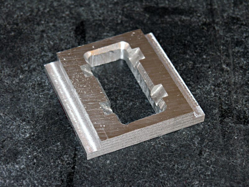 Square-shaped metal object with a central rectangular cutout.
