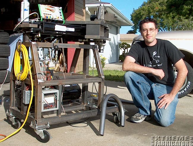 Man kneeling next to a metal work cart with various machinery tools.