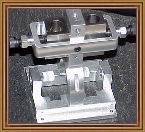 A silver metal vise with a black knob, set against a dark background.