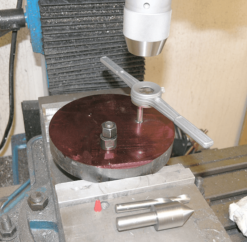 Milling machine setup with red components and drill bit holder.